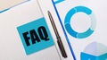 There is a pen between the blue sticky note with the text FAQ and the blue chart. Business concept. View from above Royalty Free Stock Photo