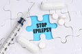 There are pills and a syringe on the white puzzles. Inside on a blue background the inscription - STOP EPILEPSY
