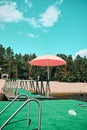 There is a pink beach umbrella on the green pier.