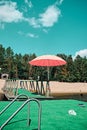 There is a pink beach umbrella on the green pier.