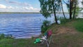 There is a place for fishing on the lake shore. There is a folding chair, a stand for a feeder rod, a bucket with bait and a box w Royalty Free Stock Photo