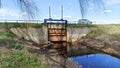 There is a river running under the road where cars drive. It has a dam with a gate to regulate the level of flood water by means o Royalty Free Stock Photo