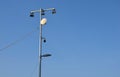 There is a row of halogens on the pole above the sports ground for the night use of the sports stadium. a rotating panoramic camer