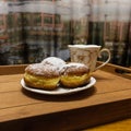 There is a saucer of donuts and a cup on a beige wooden tray. Royalty Free Stock Photo