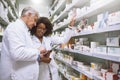 There seems to be enough of this. two focused pharmacist walking around and doing stock inside of a pharmacy.