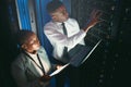 There seems to be problem with this unit. two young IT specialists standing in the server room and having a discussion