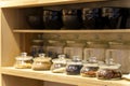 There are several glass containers of tea on the shelf. Different types of tea on the shelf in the cafe. Wooden cupboard with