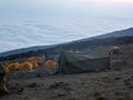 There are several tents on the mountain top above the clouds. Morning of active tourists and travelers