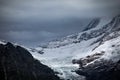 there is a snowy mountain that is next to water and rocks