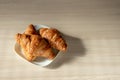 There are three croissants on the table on a white plate for breakfast Royalty Free Stock Photo