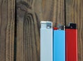 There are three lighters on a wooden surface - white, blue, red. Space for text, blank mockup on the lighter. Lighters Royalty Free Stock Photo