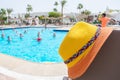 There is a tourist hat at the pool where the party takes place. A beach hat is on the background of a pool with people
