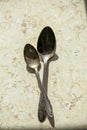 There are two beautiful antique iron spoons with patterns on the table