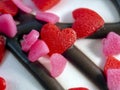 There are two red sweet hearts and many pink hearts on the white frosting and chocolate stripes. Close-up. Romantic background Royalty Free Stock Photo