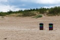 .There are two trash cans with dark lids and two-color stickers on a sandy beach Royalty Free Stock Photo