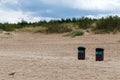 .There are two trash cans with dark lids and two-color stickers on a sandy beach Royalty Free Stock Photo