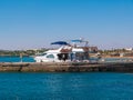 There are two white motor yachts at the pier. Against the background of Marina. Lifebuoys are attached to the sides of the boat