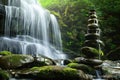 There is a waterfall behind and a pile of rocks in the foreground Royalty Free Stock Photo