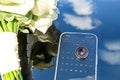 There are wedding rings with a bouquet of flowers on the phone. The sky is reflected Royalty Free Stock Photo