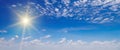 There are white cumulus clouds and a sun in the blue sky. Wide photo Royalty Free Stock Photo