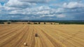 Fly over a golden wheat field. A tractor with a baler collects straw into bales.