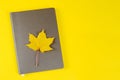 There is a yellow maple leaf on a gray notebook-diary Royalty Free Stock Photo