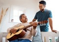Theres magic in music. a young man listening to his father play the guitar at home.