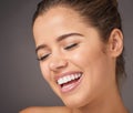 Theres so much beauty in happiness. Studio shot of a beautiful young woman laughing against a gray background.