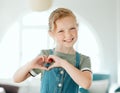 Theres so much love in our home. an adorable little girl standing alone at home and making a heart sign gesture.