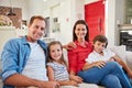 Theres no greater joy than family. Portrait of smiling parents sitting with their young son and daughter on their living Royalty Free Stock Photo