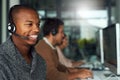 Theres no issue they cant help you resolve. a call centre agent working in an office with his colleagues in the Royalty Free Stock Photo