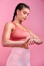 Theres no time to waste time. Studio shot of a sporty young woman checking her watch against a pink background. Royalty Free Stock Photo