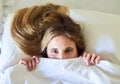 Theres no way Im leaving this bed today. Portrait of a playful young woman hiding under the covers in her bed.