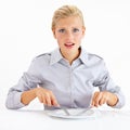 Theres nothing here. Dismayed young woman sitting in front of an empty plate while holding her knife and fork. Royalty Free Stock Photo