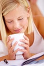 Theres nothing like the smell of freshly brewed coffee. Young woman smelling a cup of coffee while lying down.
