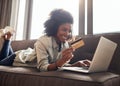 Theres nothing wrong with spoiling yourself. a young woman holding her credit card while using her laptop.