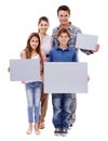 Theres something for all of us. Portrait of a family of four holding up a blank placard for copyspace, isolated on white