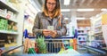 Theres always time for social media, even when grocery shopping. a young woman using a mobile phone in a grocery store. Royalty Free Stock Photo