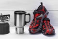 Thermo mug and red shoes for traveling on a light gray background