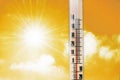 Thermometer against the background of an orange yellow hot glow of clouds and sun, concept of hot weather. Royalty Free Stock Photo