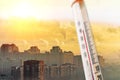 Thermometer against the background of a polluted city smog during hot weather. Royalty Free Stock Photo