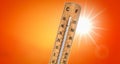 Thermometer against orange background with hot summer sun. Royalty Free Stock Photo