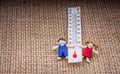Thermometer between a boy and a girl figurine Royalty Free Stock Photo