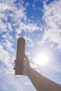 Thermometer in hand against the blue sky with clouds and sun Royalty Free Stock Photo