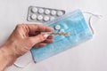 thermometer in the hands of a woman. Pills and a medical mask on the table. Close-up