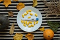 thermometer lies next to yellow pills on a plate on the table in the kitchen with leaves and pumpkin nearby, medicine Royalty Free Stock Photo