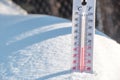 The thermometer lies on the snow and shows a negative temperature in cold weather on the blue sky.Meteorological conditions with