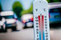 Thermometer showing high temperature in front of traffic during heatwave