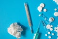 Thermometer, syringe, ampoules, pills and crumpled paper napkin on blue paper background. Concept of common cold, covid