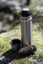 Thermos, cup and pinecone- picnic on mossy rock